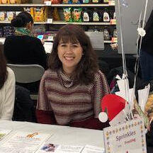 It's a smiling young woman pictured at the table of a service event at a local community center.